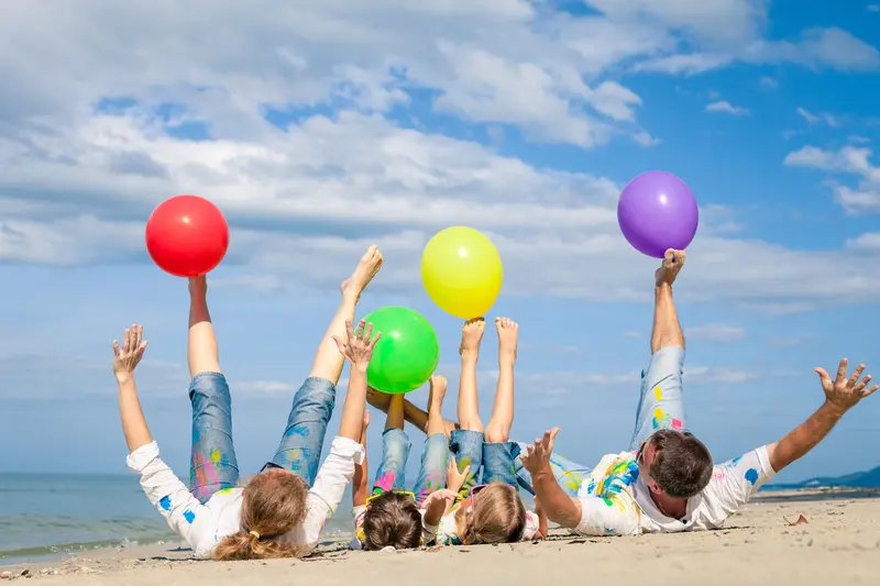 Enfants couchés sur la plage jouant avec des ballons